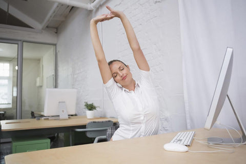 Office worker stretching at her desk